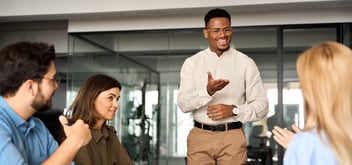 Image of a male speaking with other people in a an office space 